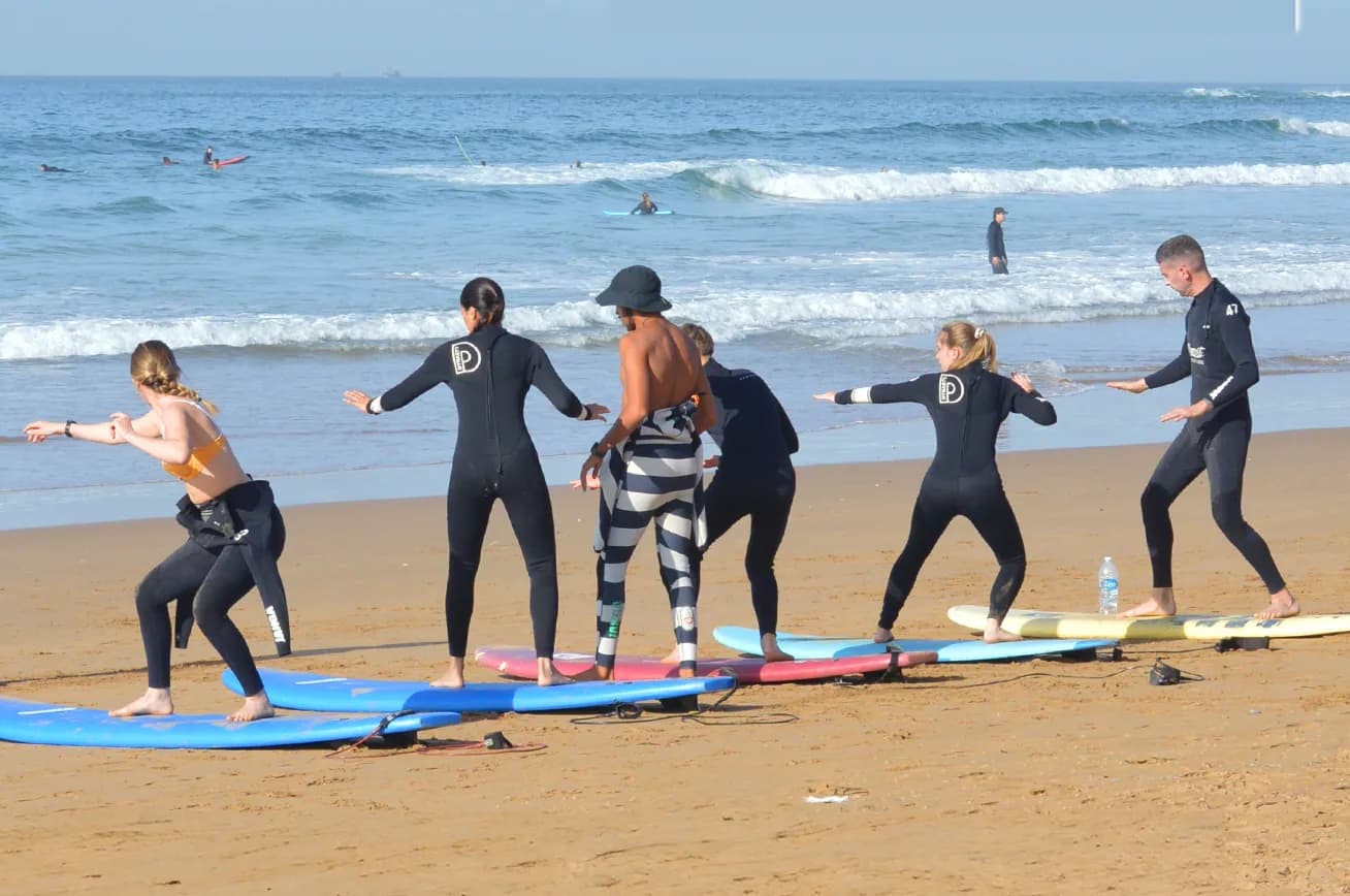 A surf guide carrying colourful boards from the trailer down to the beach
