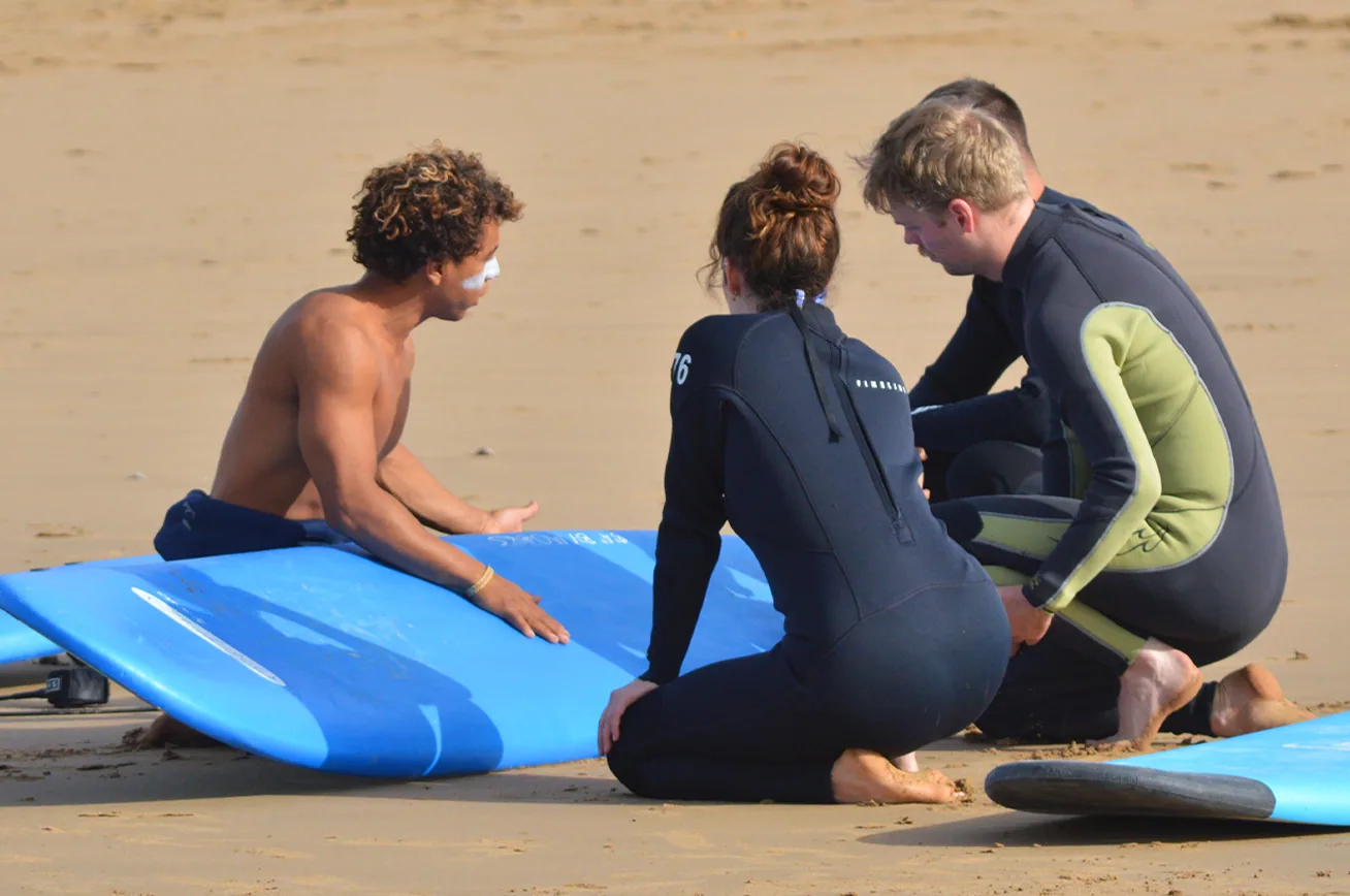 A surf coach briefing students on the beach before a lesson in Tamraght