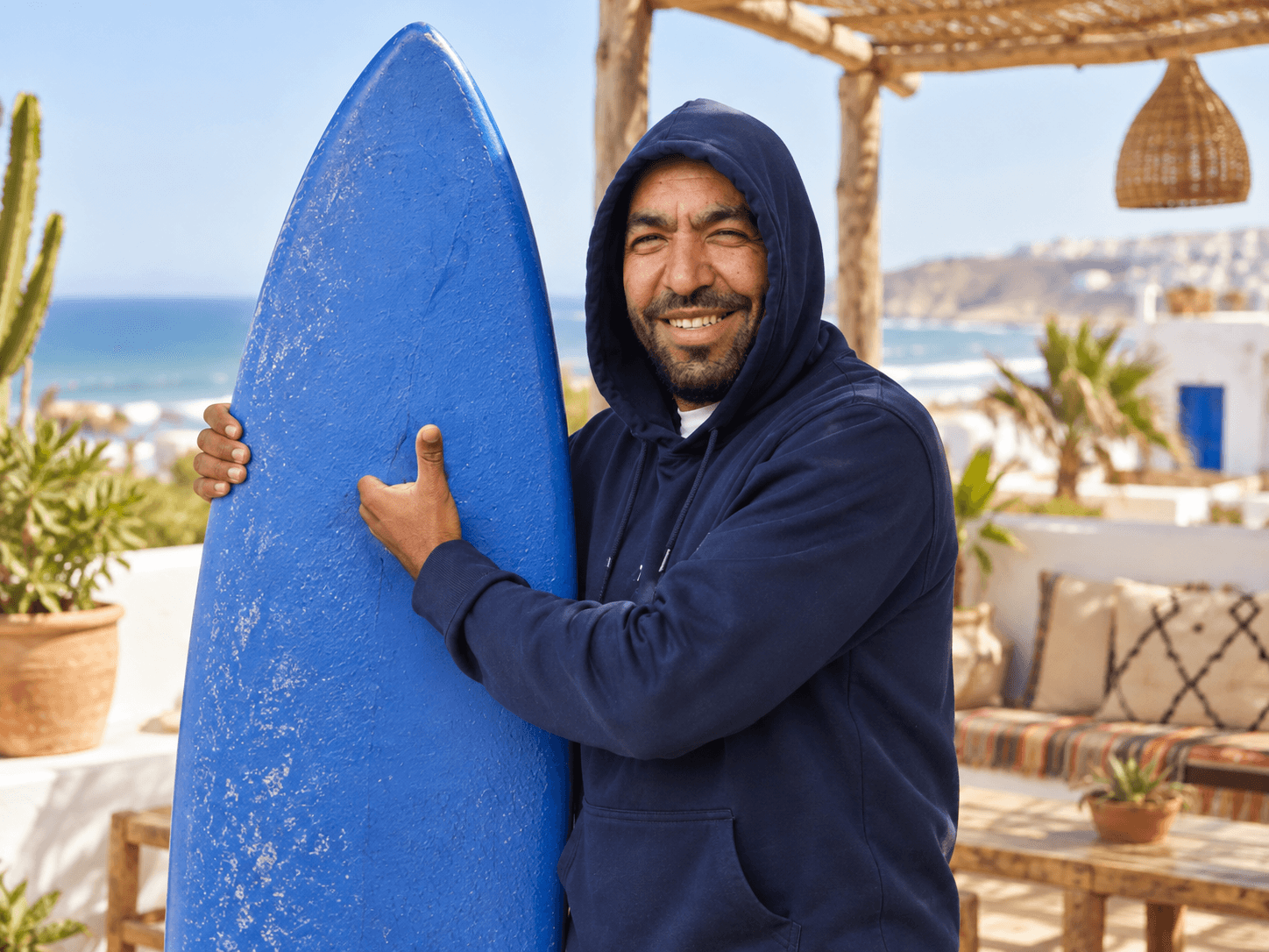 Abdoull smiling beside a blue surfboard