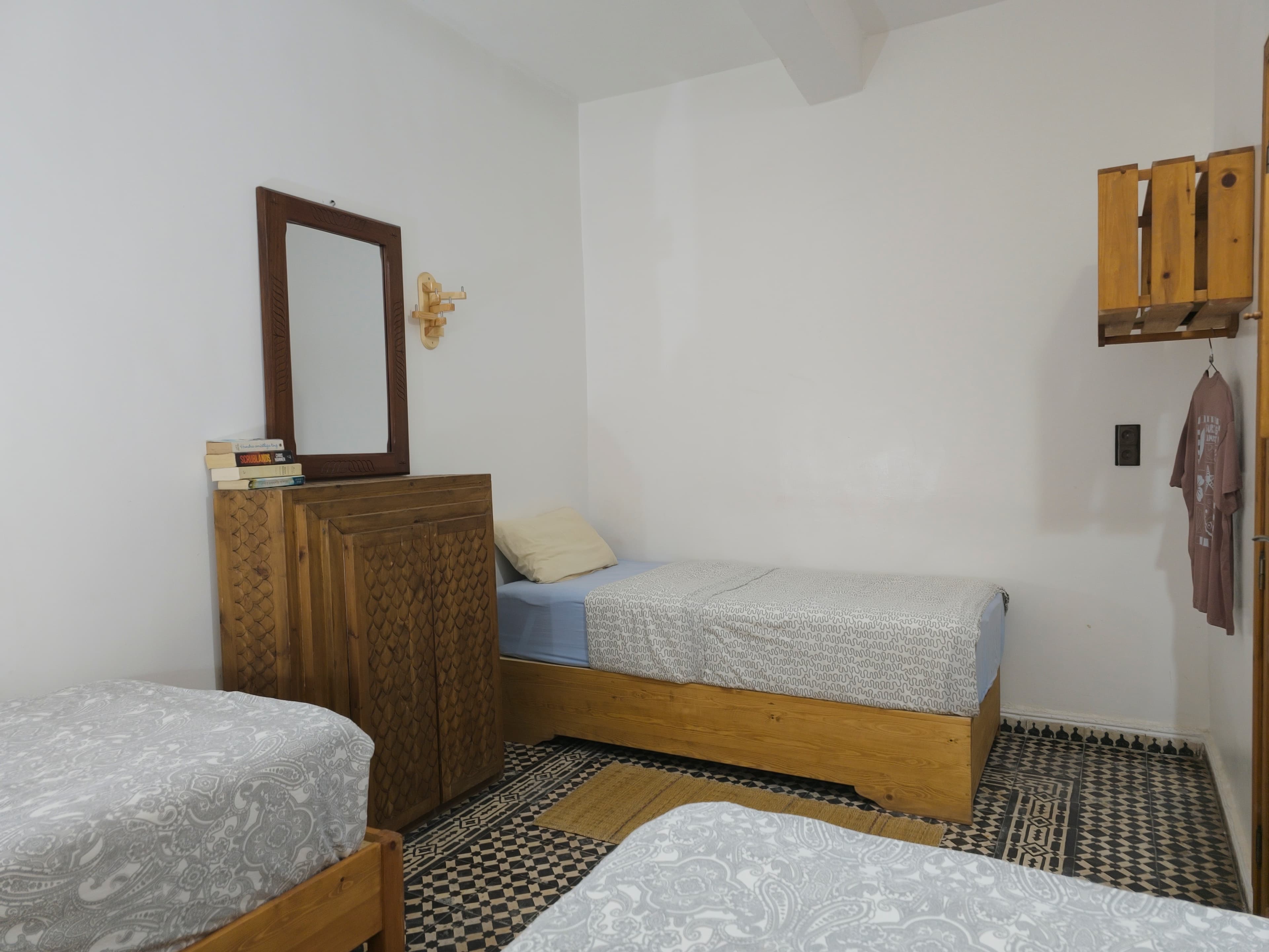 Single room at Sunset Surf House with wooden headboard and cozy Moroccan bed