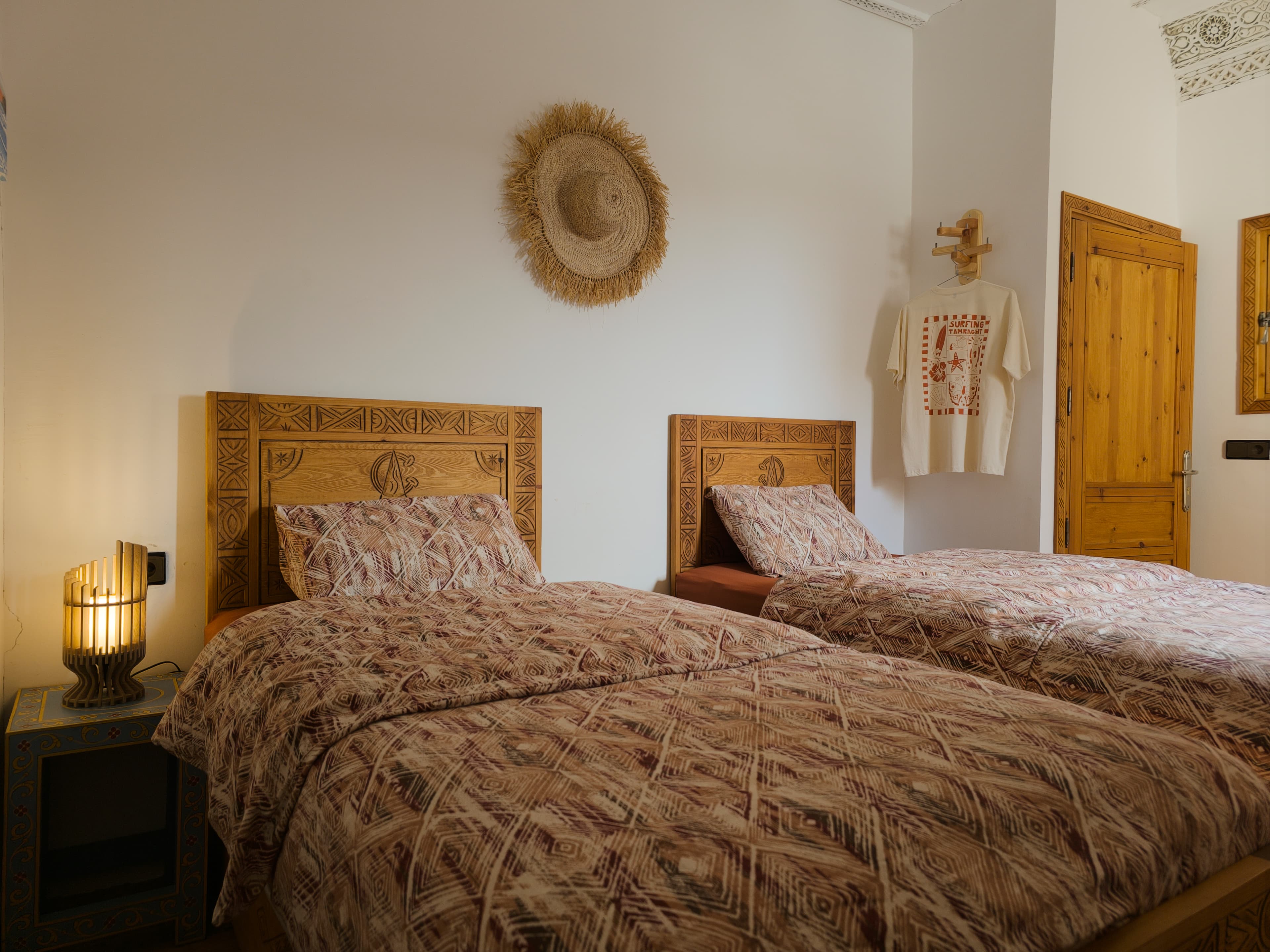 Cozy room with traditional Moroccan patterned bedspread and carved wood headboard at Sunset Surf House